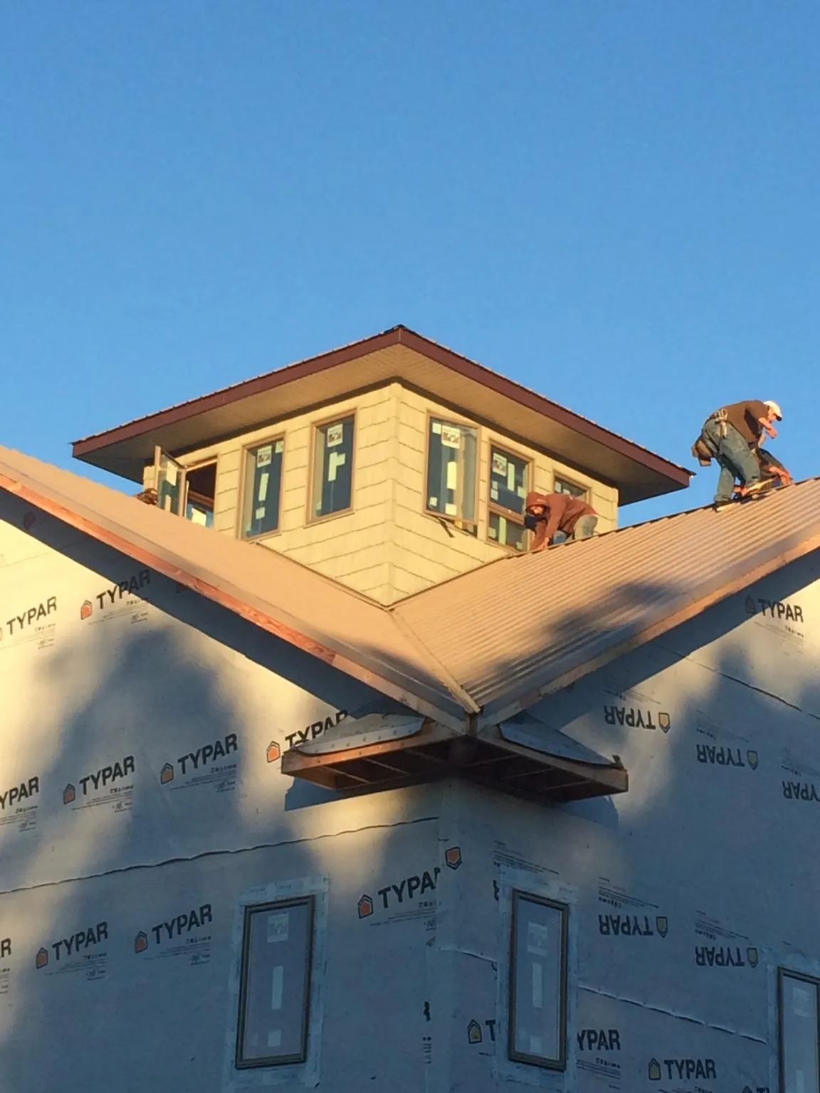 Roofers working around a rooftop cupola on a new metal roof at sunset — Roof Waterproofing in Warwick by Roofing Brothers